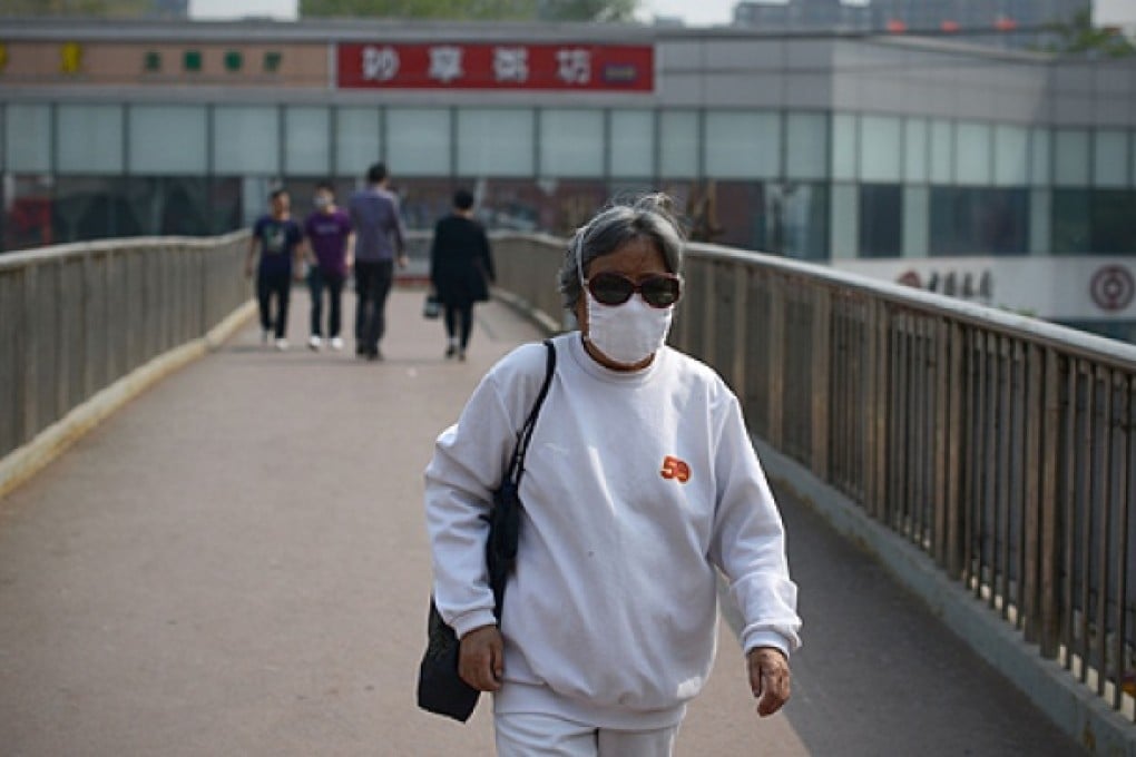 A woman wears a face mask as she walks on an overpass in Beijing. Photo: AFP