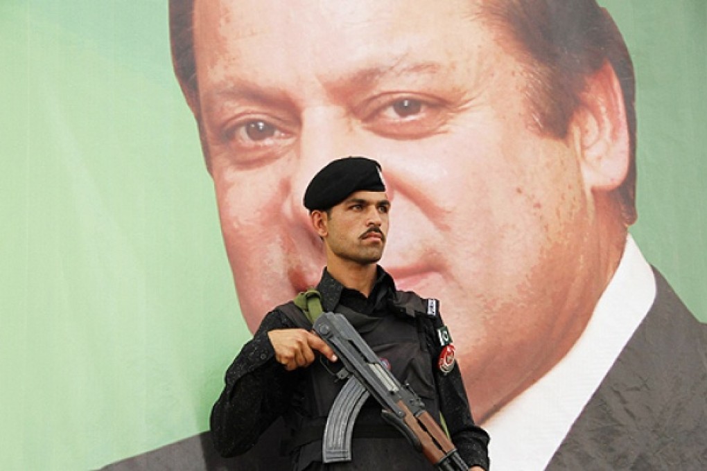 A paramilitary soldier guards in front of the portrait of Nawaz Sharif, leader of political party PML-N, during an election campaign rally in Peshawar. Photo: Reuters