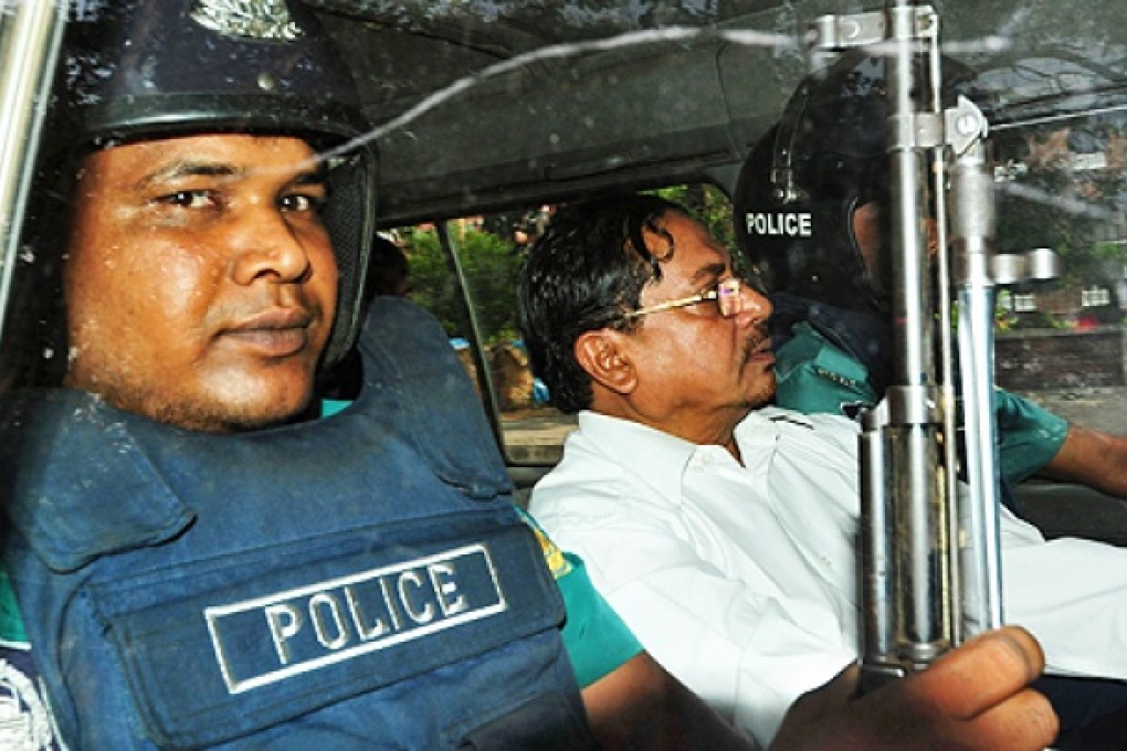 Bangladeshi Jamaat-e-Islami leader, Mohammad Kamaruzzaman, sits next to a police officer as he leaves court in Dhaka on Thursday. Photo: AFP