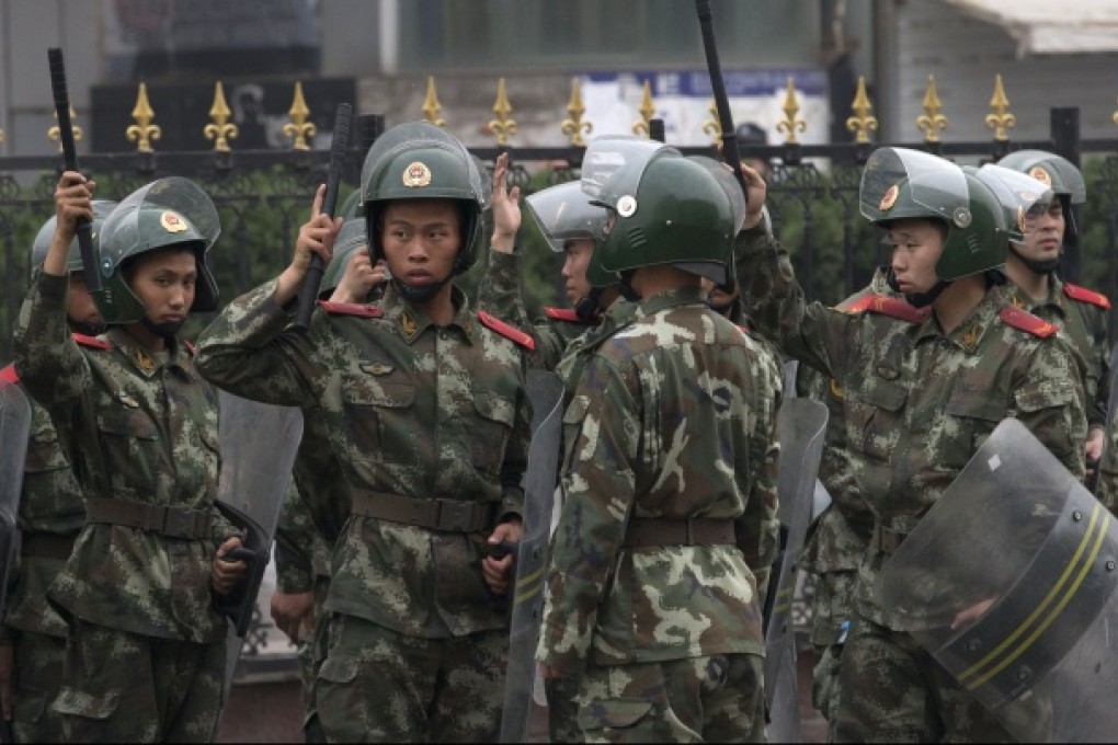 Chinese paramilitary policemen on duty stand outside a clothing wholesale mall where a woman fell to her death on May 3, in Beijing, May 8, 2013. Photo: AP
