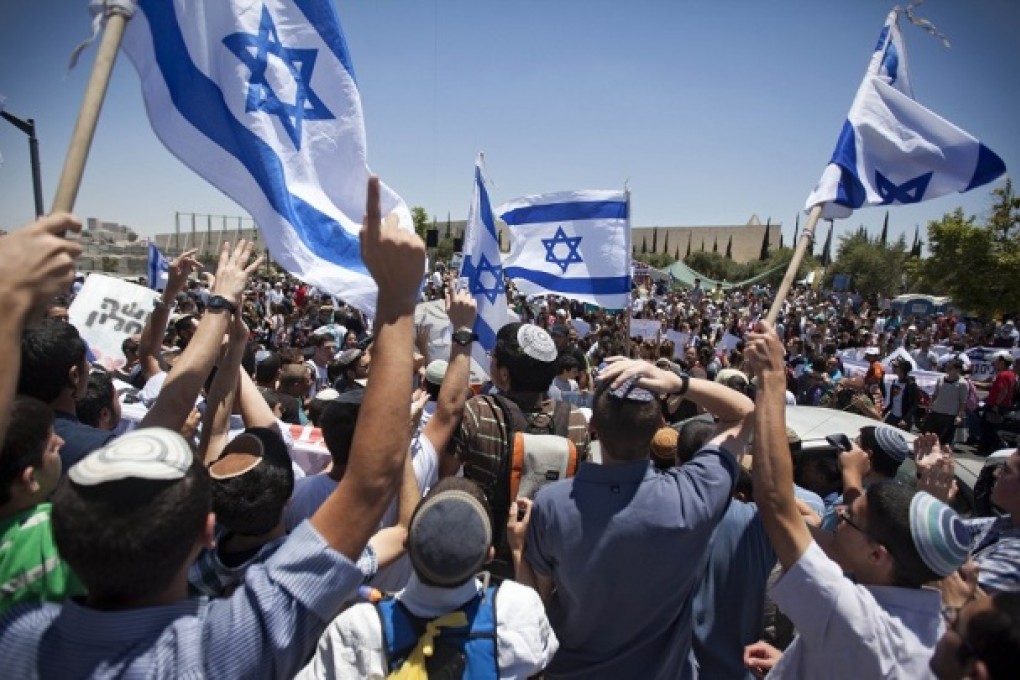 Jewish settlers wave Israeli flags during a recent protest over the West Bank settlement of Beit El near Ramallah. Photo: AP