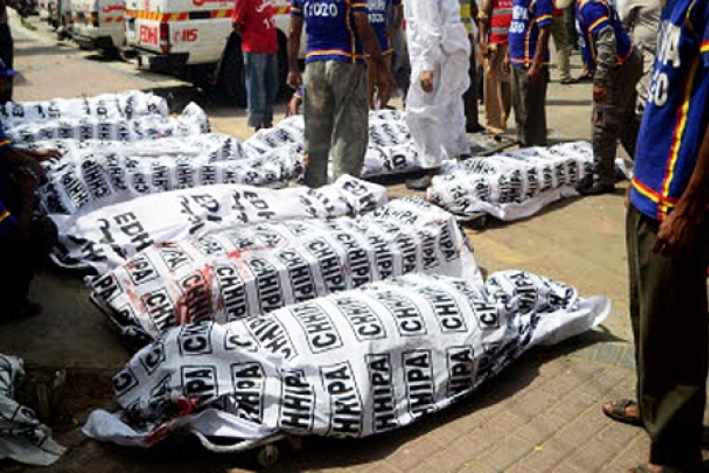 Pakistani volunteers gather beside the dead bodies of blast victims outside a hospital following a bomb explosion in Karachi on Saturday. Photo: AFP