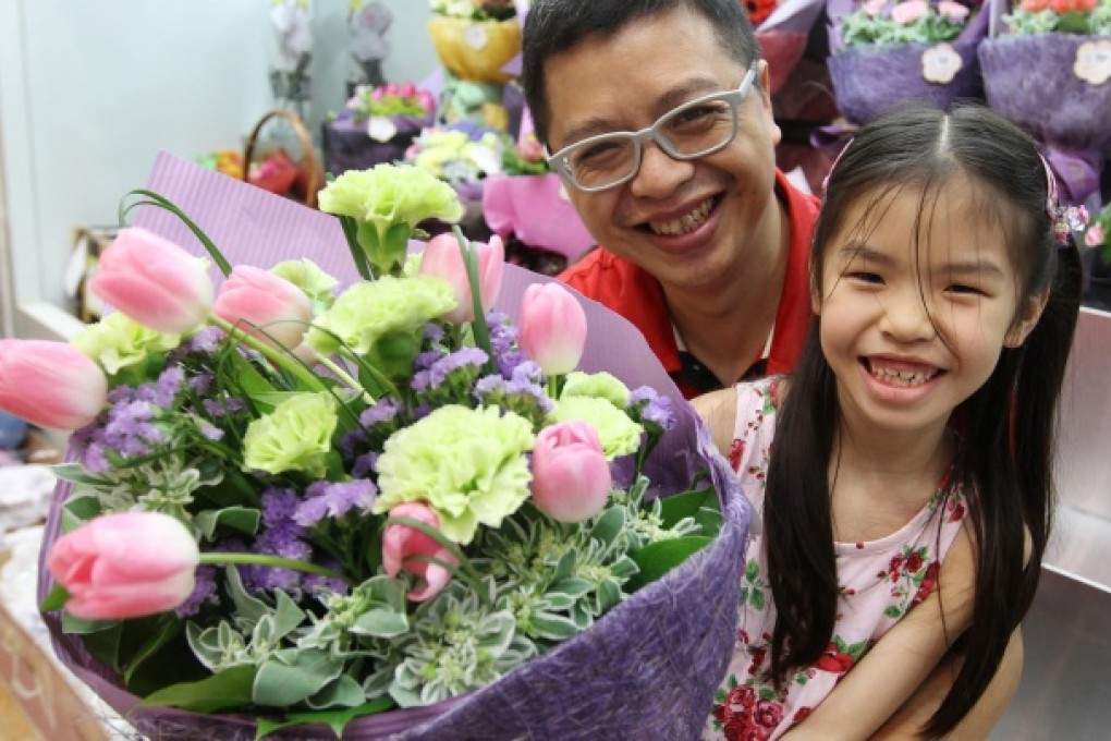 As crowds throng the shops on Flower Market Road in Mongkok, Tam Ka-fai helps his seven-year-old daughter Beatrice to buy a bouquet for her mother to celebrate Mother's Day, which falls today. Photo: Edward Wong