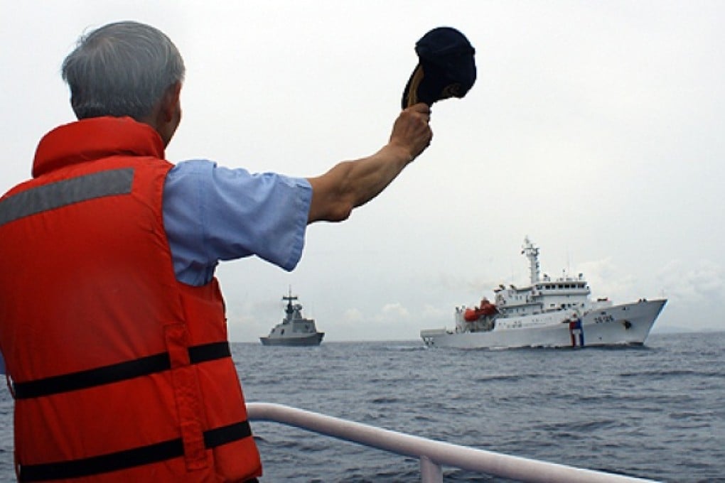 A Taiwanese coastguard official waves his cap as a fleet of naval and coast guard frigates sets sail from Kaohsiung. Photo: AFP