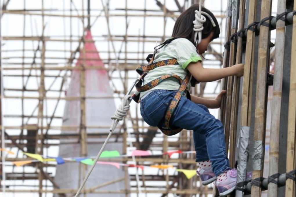 Four-year-old Wong Yuen-yan scales the bun tower outside Pak Tai Temple on Cheung Chau island yesterday. The event allowed children to climb the metal tower to be used for this Saturday's bun-scrambling contest during the island's popular Bun Festival. The plucky little girl managed to climb to the top of the structure, which was about 18 metres high, and won the applause of onlookers. Photo: Dickson Lee