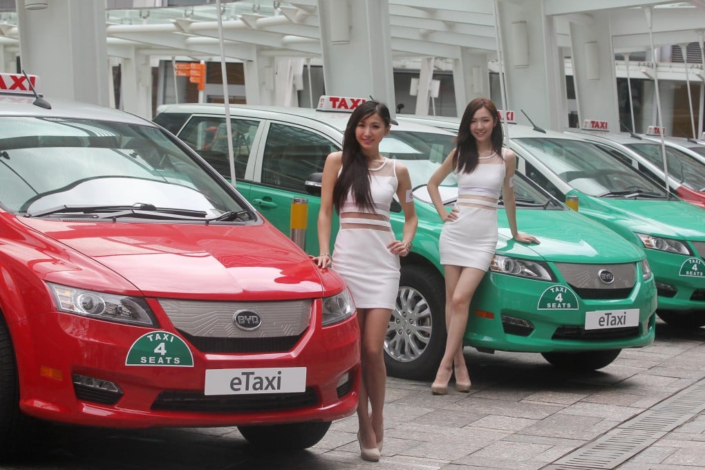 Two models try their best to make the eight-months' late eTaxis look more appealing at yesterday's launch ceremony. Photo: K. Y. Cheng