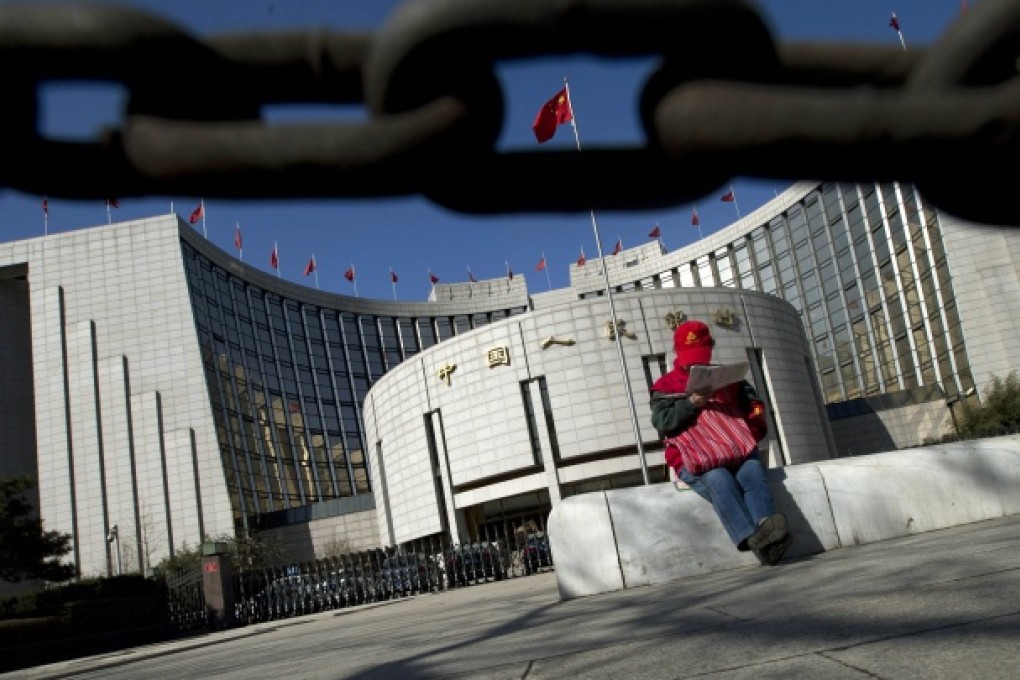 A woman reads the newspaper outside the People's Bank of China in Beijing. Photo: AP