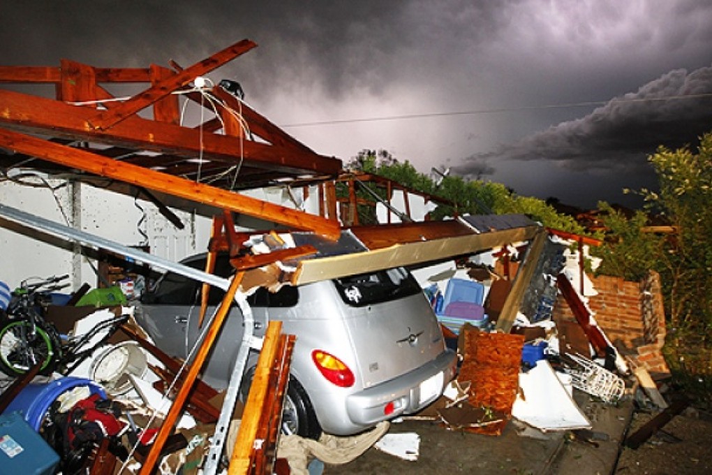 Lightning strikes from a storm illuminate a home damaged by a tornado on Wednesday night. Photo: AP