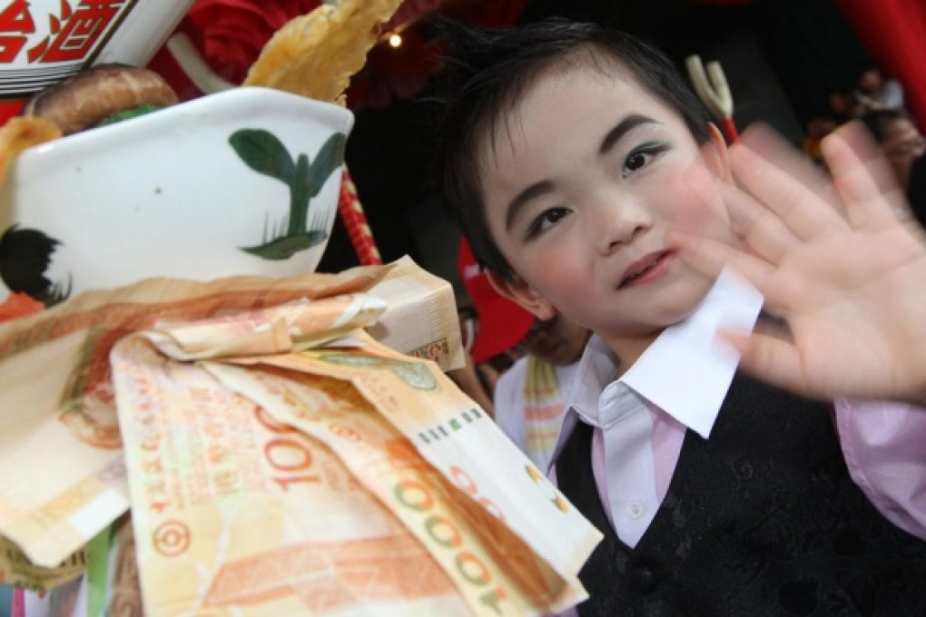 A boy dressed as ex-ICAC chief Timothy Tong Hin-ming, makes light of the corruption allegations surrounding the former graft-buster during the Cheung Chau Bun Festival yesterday. The props used to mock Tong, who allegedly treated mainland officials to lavish entertainment, included a bowl of dried seafood and eight HK$1,000 notes. Photo: K. Y. Cheng