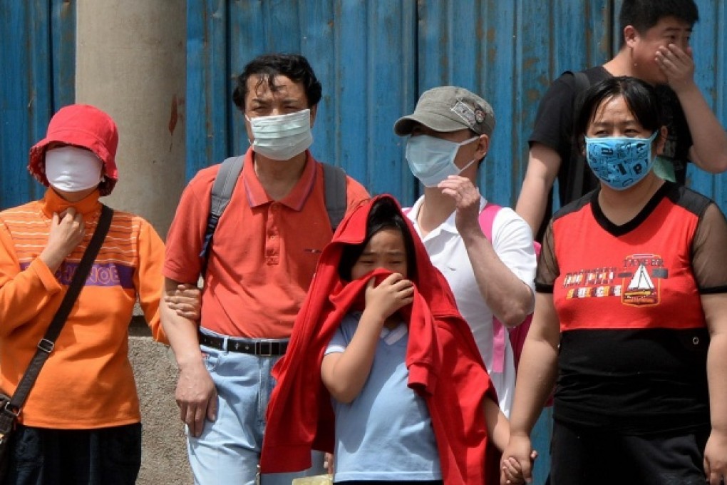 Beijing residents cover up as they brave the air pollution - and later thick dust and sand - yesterday. Photo: AFP