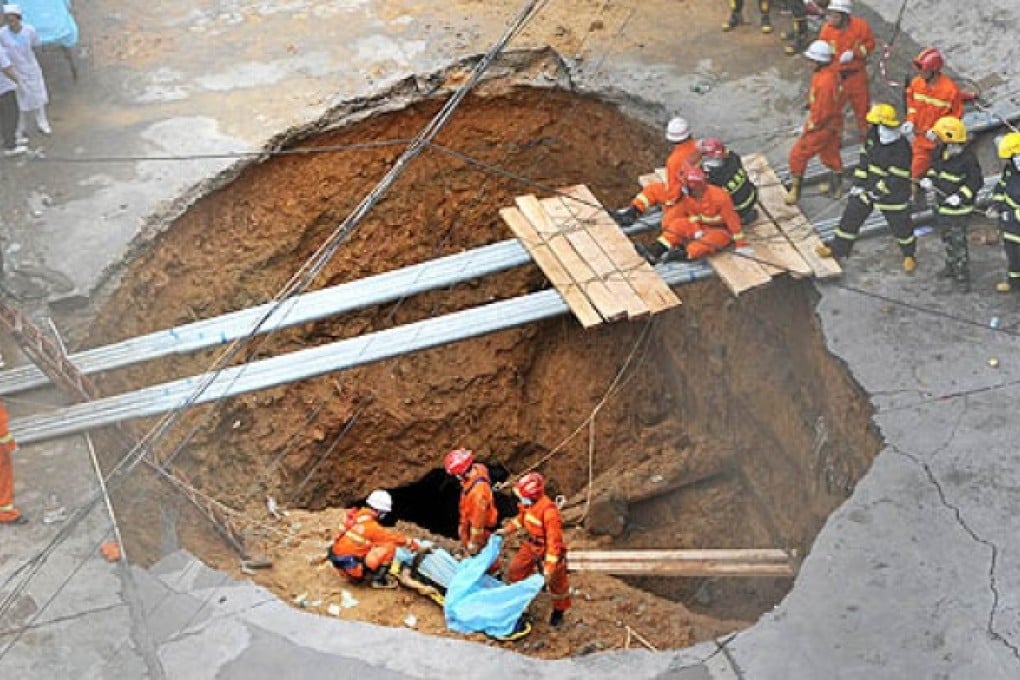 Rescuers prepare to move a dead body found in a sinkhole on a road in Shenzhen, south China's Guangdong province, on Tuesday. Photo: AFP