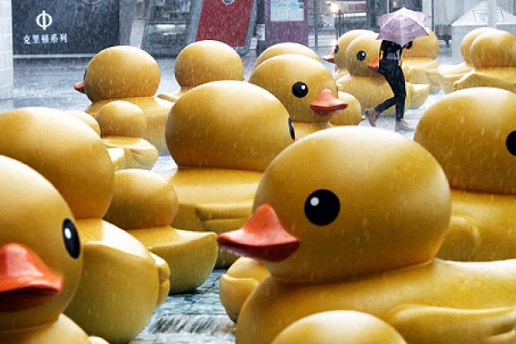 Pedestrians walk pass rubber ducks outside Harbour City in Tsim Sha Tsui as rainstorm hits the city on Tuesday. Photo: David Wong