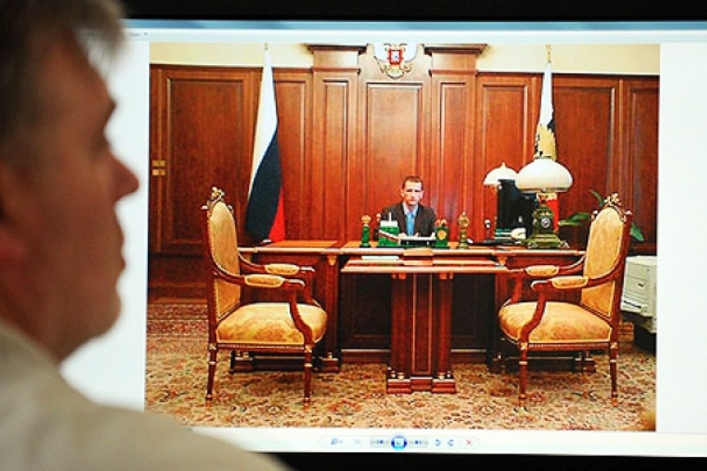 A man looks at a computer screen displaying one of the pictures of Alexei Ustimchuk posing behind Vladimir Putin's desk in the Kremlin, on Tuesday. Photo: AFP