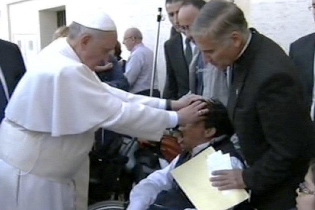 Pope Francis lays hands on a young man's head after Mass. Photo: AP