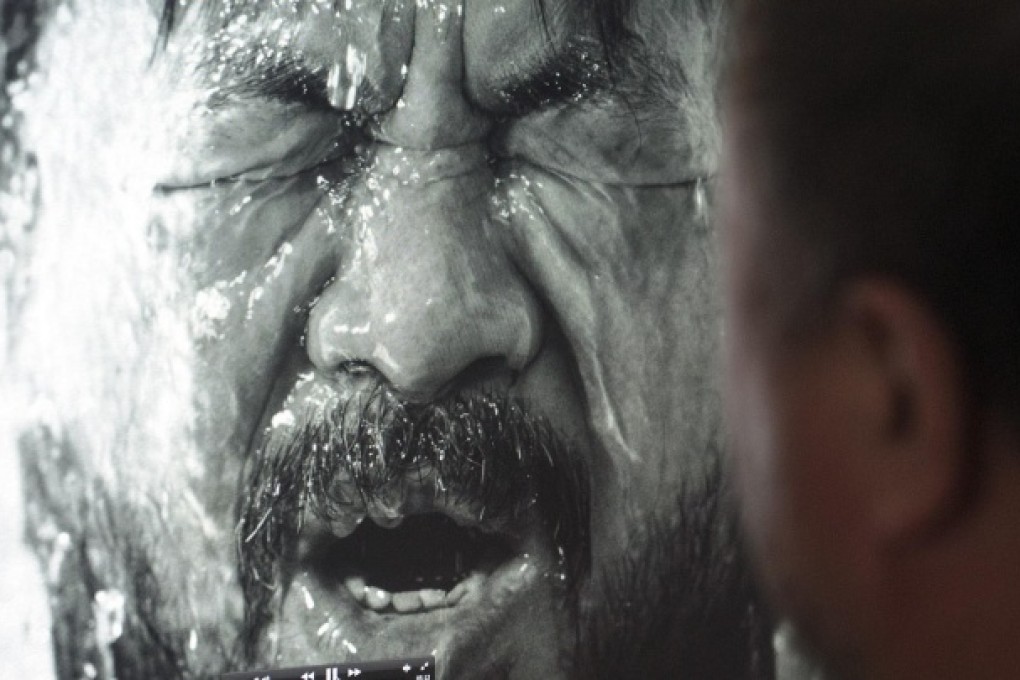 Ai Weiwei watches a video recreating his detention. The artist has released a music video and album that touches on the episode. Photo: NYT