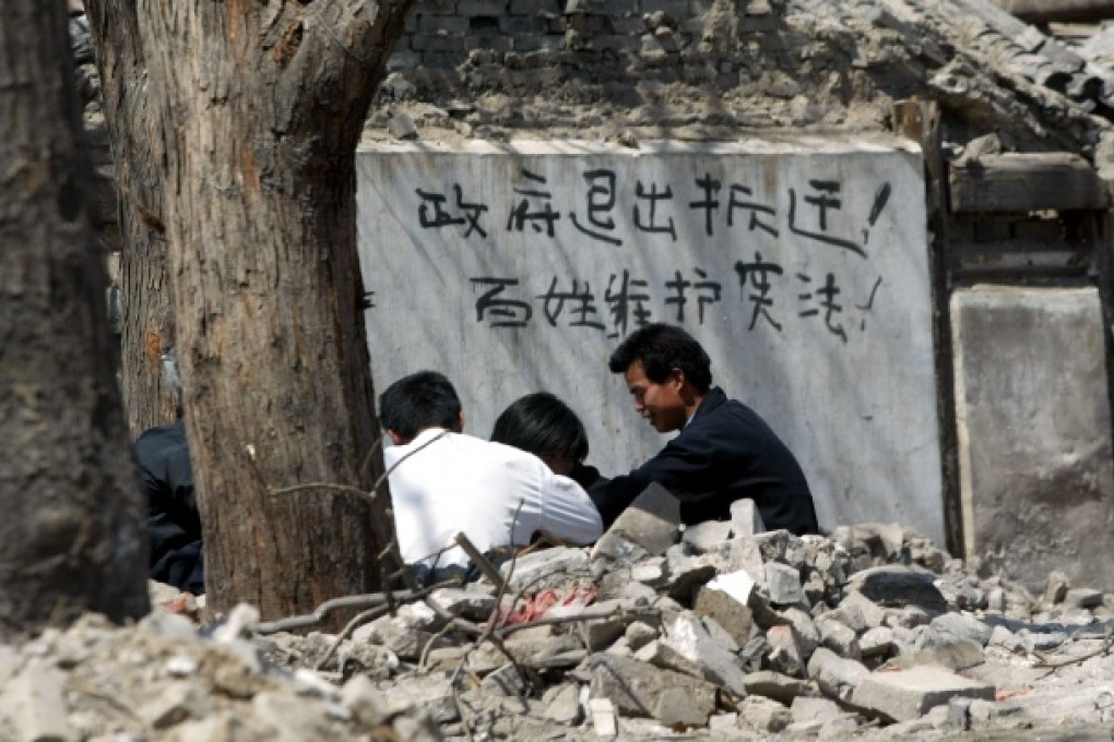 Chinese words reading "Government get out of the eviction business, commoners protect the constitution" are painted on a house marked for forced eviction in Beijing in 2004. Photo: AP