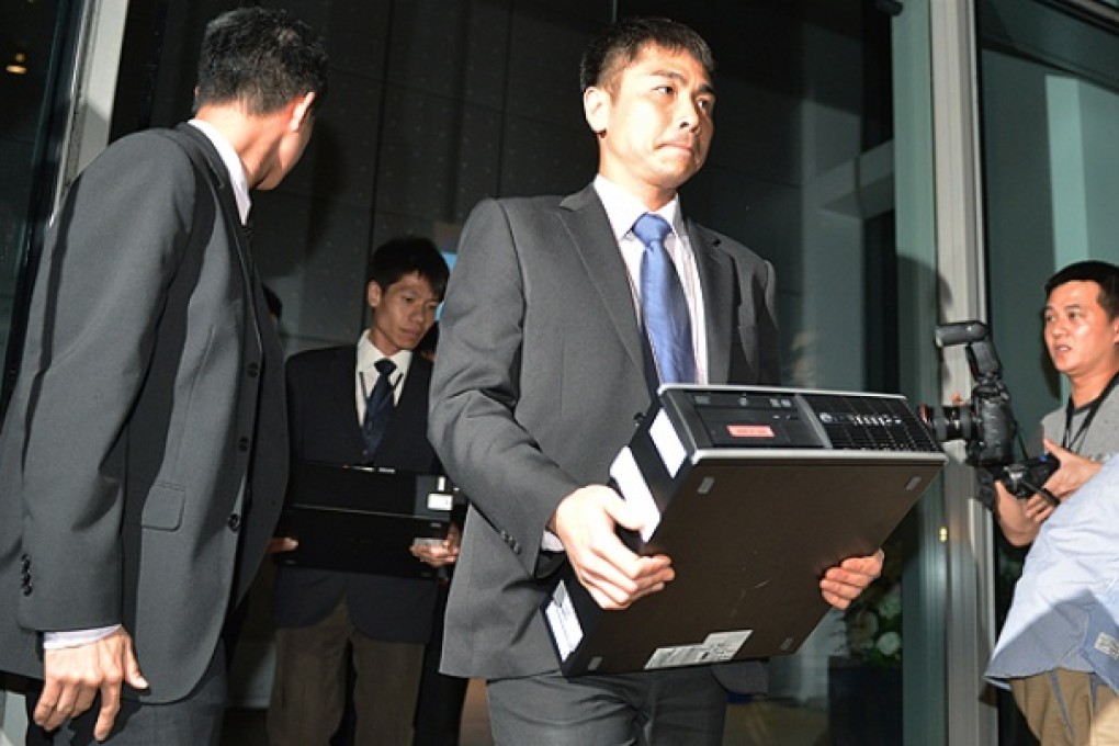 Police officers emerge with evidence from the Hong Kong Mercantile Exchange’s office at Cyberport last night. Photo: Thomas Yau