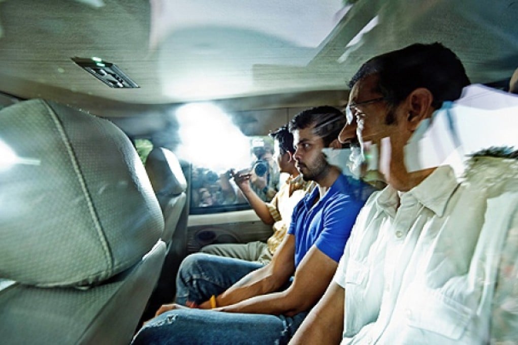Indian cricketer Shanthakumaran Sreesanth (centre) sits in a police vehicle as he leaves the Saket district court in New Delhi on Tuesday. Photo: AFP