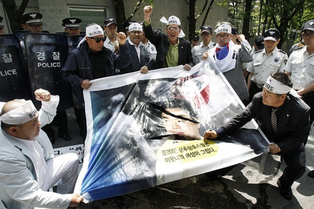 A South Korean protester uses a knife to tear a portrait of Japanese Mayor of Osaka Toru Hashimoto during a rally against Japan in front of the Japanese ambassador's residence in Seoul, South Korea, on Tuesday. Photo: AP