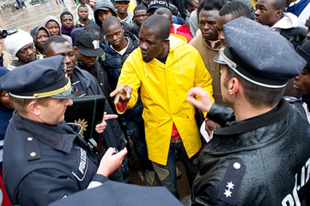Refugees from Libya talk to German police officers as they stage a protest in front of the city hall in Hamburg, northern Germany on Wednesday to raise awareness of their current living conditions. Photo: AFP