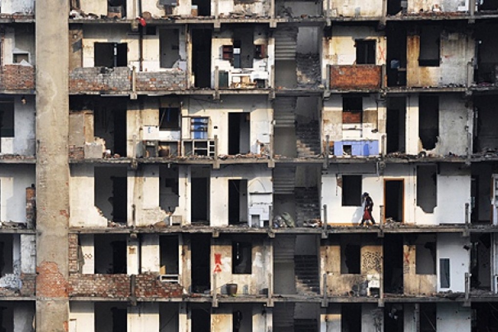 A rubbish collector walks through a building due to be torn down to make room for a new residential area in Wuhan, Hubei province. Photo: Reuters