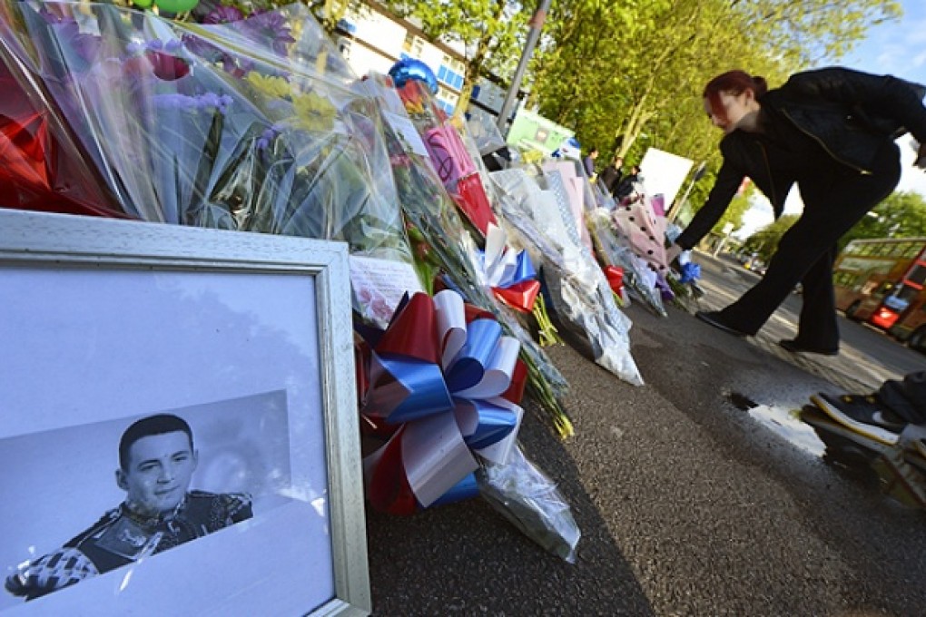 A picture of victim Lee Rigby of the Royal Regiment of Fusiliers is displayed with flowers near the scene of his killing in Woolwich. Photo: Reuters