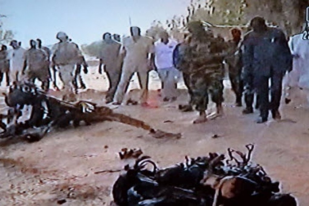 A video grab shows people standing in front of wreckage of the suicide bomber's motor vehicle at the Agadez army base, Niger, following car bombings in Niger in which at least 20 people died. Photo: AFP