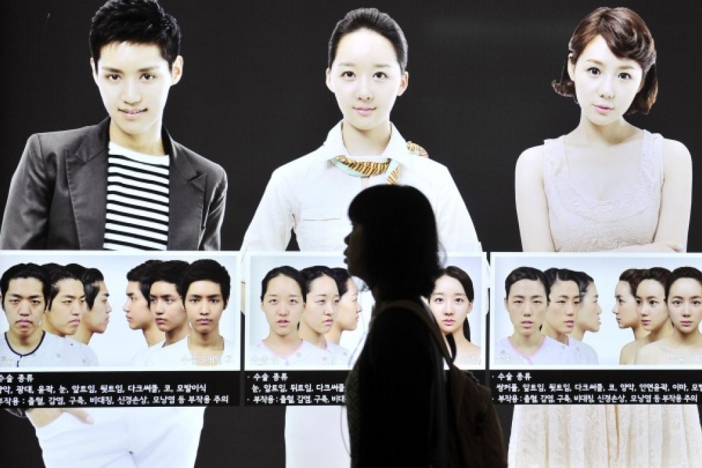 A woman passes a billboard in Seoul advertising double-jaw surgery for cosmetic purposes. "Everyone but you has done it," some of the posters claim. Photo: AFP