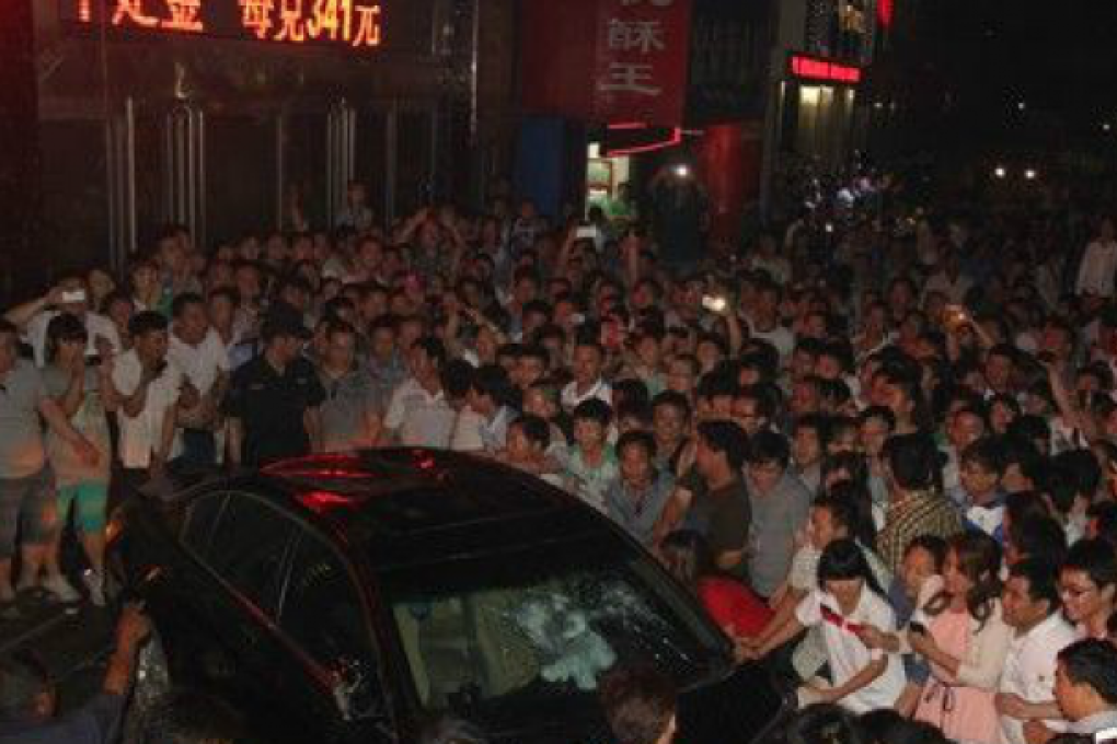 A crowd smashes a car in Jiyuan, Henan on Friday. Photo: Screenshot from Sina Weibo