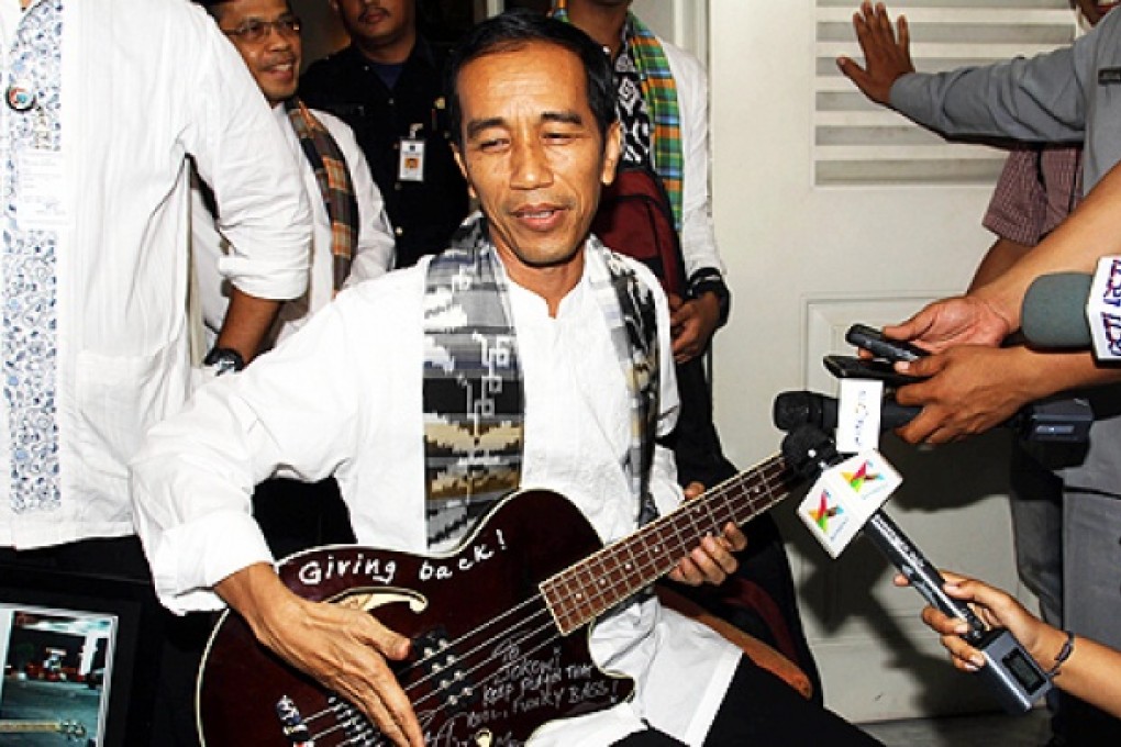 Joko Widodo with his bass guitar gift from Metallica. Photo: AFP