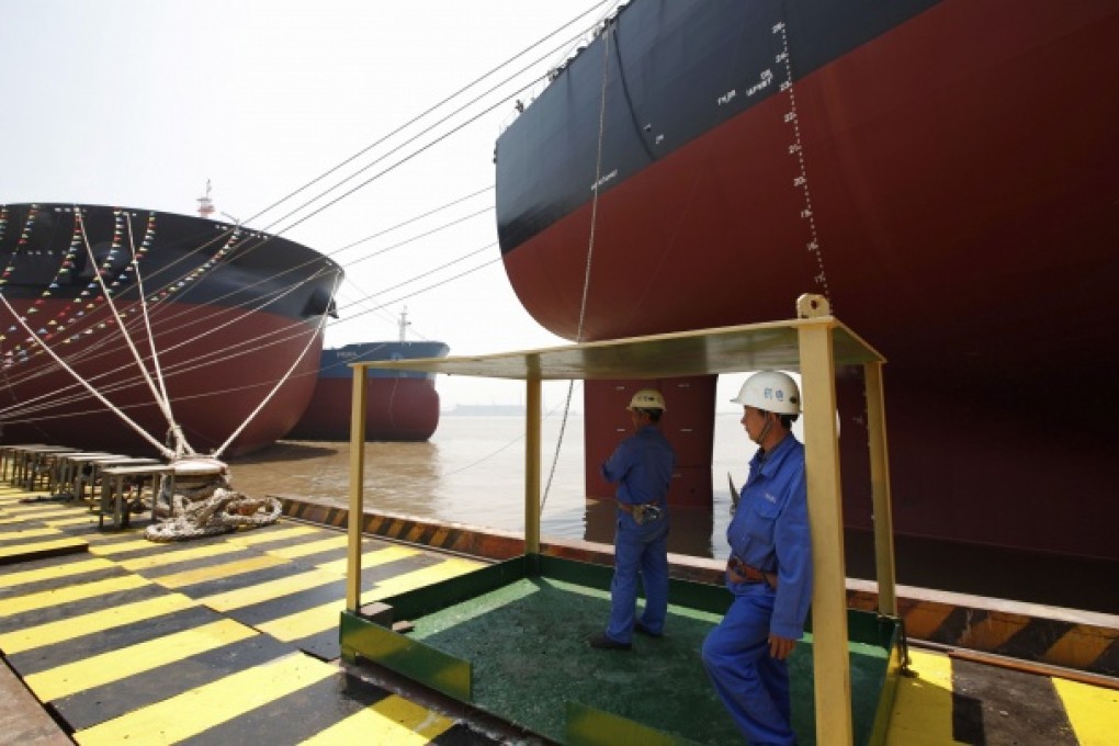 Workers stand beside a VLOC during a ship naming ceremony in Nantong. Photo: Reuters