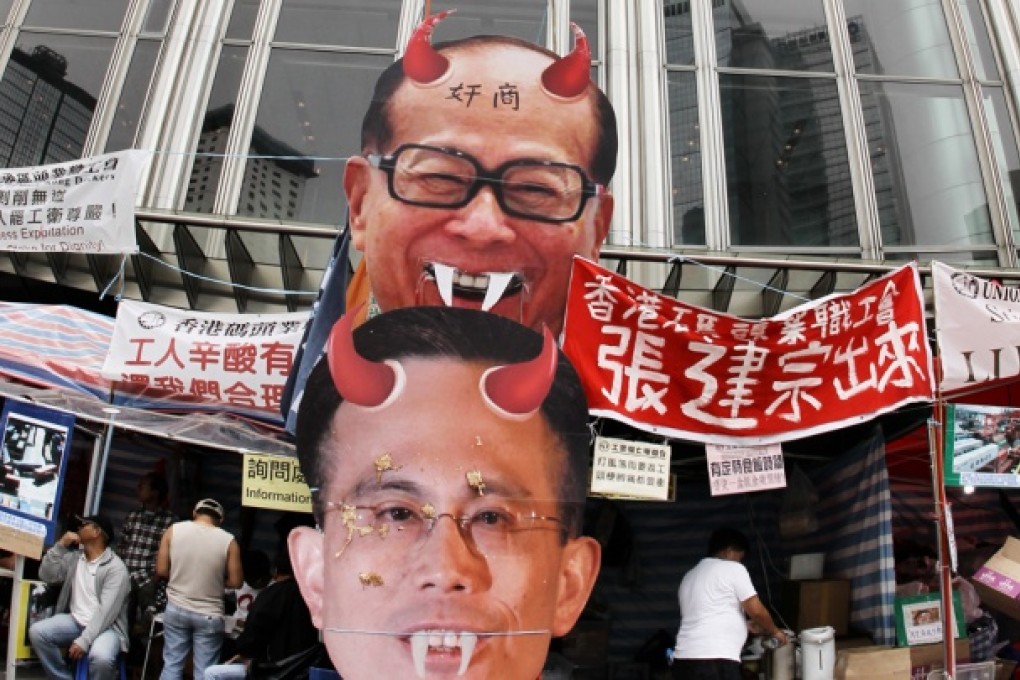 Striking dock workers put pictures of Victor Li Tzar-kuoi and his father Li Ka-shing at Cheung Kong Center in Central to voice their discontent over the poor working conditions in Kwai Chung Container Terminal. Photo: Edward Wong