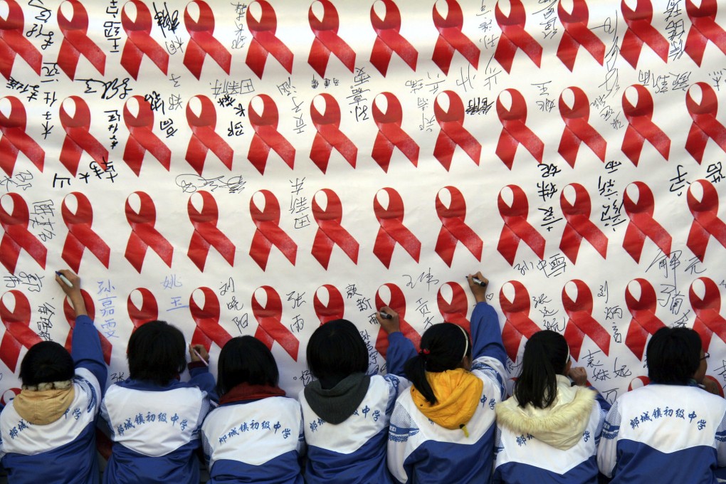 Schoolchildren write their names on a banner promoting Aids prevention and education. Photo: Xinhua
