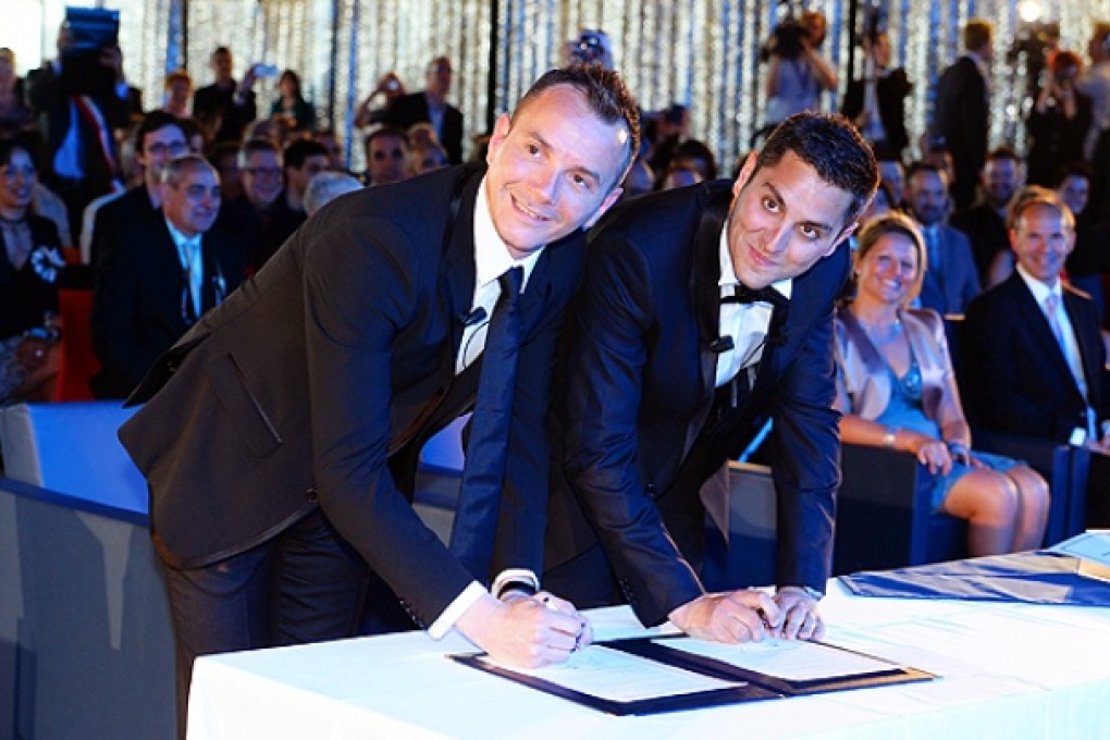 Vincent Autin and Bruno Boileau smile as they sign a document during their marriage ceremony at the city hall in Montpellier. Photo: AFP