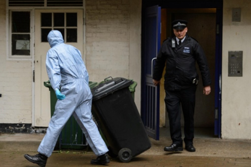 A forensics officer removes items from a flat where Michael Adebowale is registered as living. Photo: AP