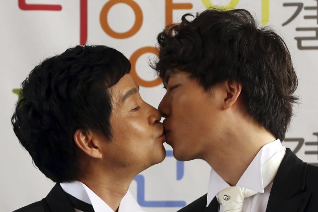 Movie director Kim Jho Gwang-soo, left kisses his partner, Dave Kim, at a news conference announcing their 'marriage' in Seoul. Photo: AP