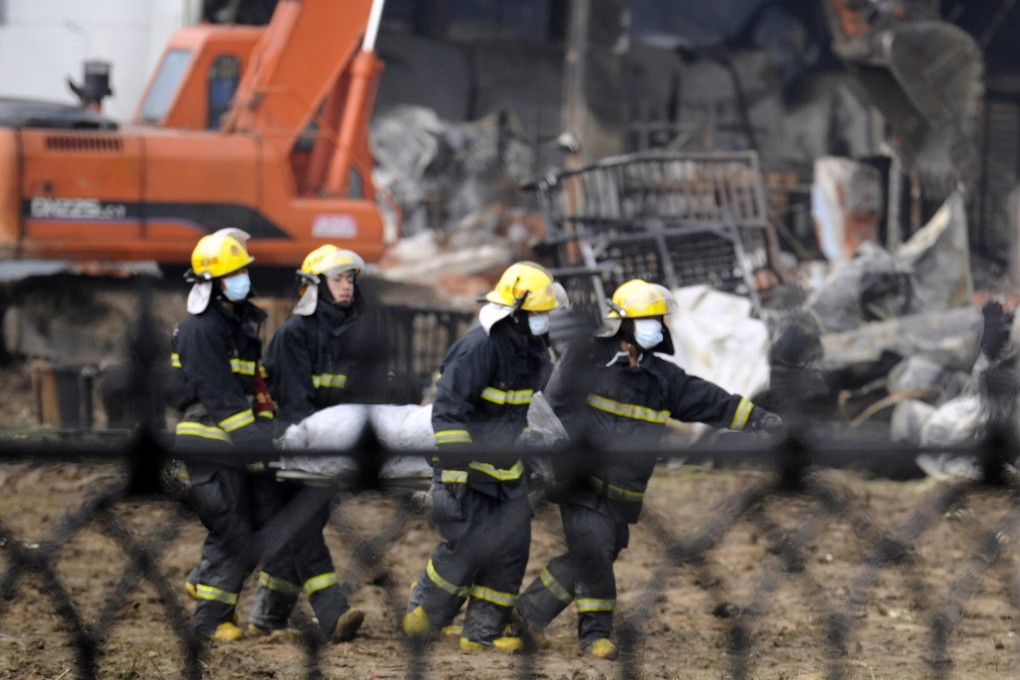 Rescuers wearing masks carry away a body - witnesses said the blaze may have been caused by leaking liquid ammonia. Photo: CNS
