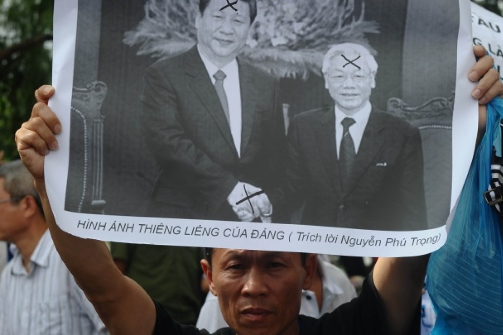 A protester holds up a photograph showing Vietnamese communist party Secretary General Nguyen Phu Trong shaking hands with Chinese President Xi Jinping during an anti-China rally in downtown Hanoi on June 2, 2013. Photo: AFP