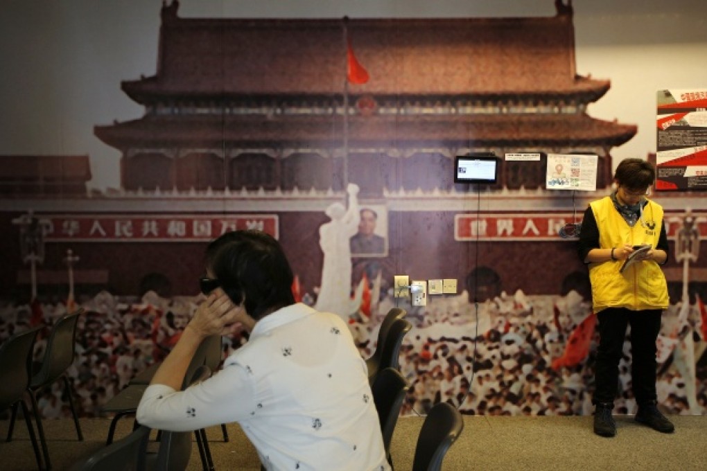 A woman watches a video footage of the crackdown of the June 4, 1989 pro-democracy movement in Beijing's Tiananmen Square with an enlarged photo of the protest as a backdrop at the "June 4 Memorial Museum" in Hong Kong's City University. Photo: AP