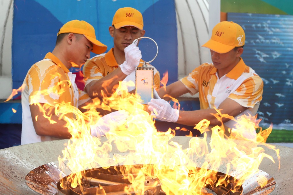 Flame guards light the lantern from the cauldron during the 2nd Asian Youth Games flame-lighting ceremony in Nanjing, capital city of Jiangsu. Photo: Xinhua