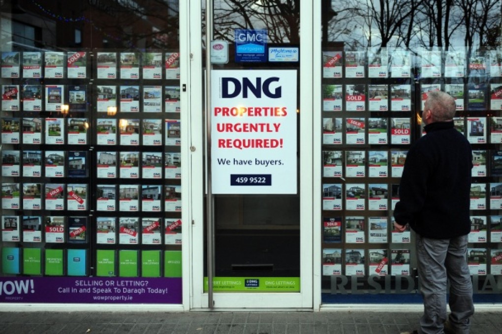 A man browses residential properties for sale in the window of an estate agent in Dublin, Ireland. Photo: Bloomberg