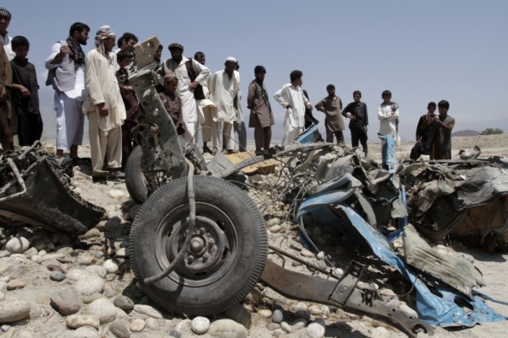 Afghans look at a destroyed vehicle after it was hit by a road side bomb in the Alingar district of Laghman province, east of Kabul, Afghanistan. Photo: AP