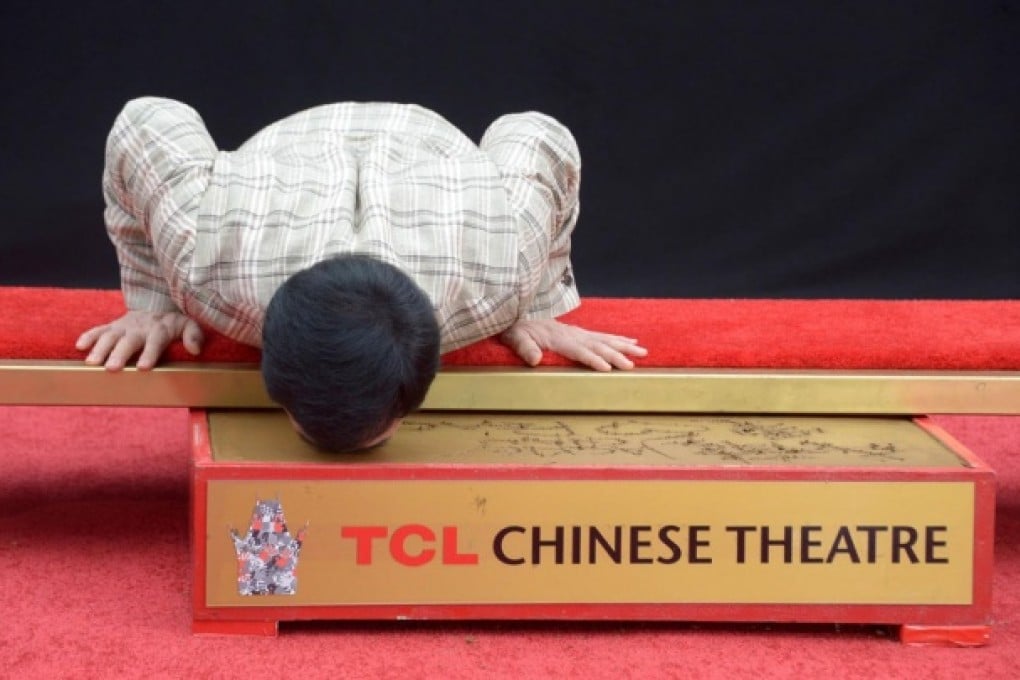 Jackie Chan sticking his nose in it to leave his imprints at the TCL Chinese Theatre in Hollywood on Thursday. Photo: Reuters