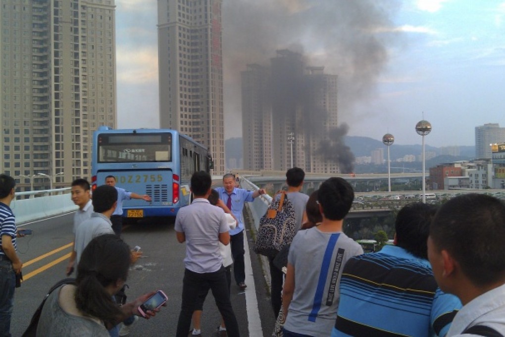 Bus drivers try to keep passengers away from the direction of a bus that burst into flames in Xiamen. Photo: AP