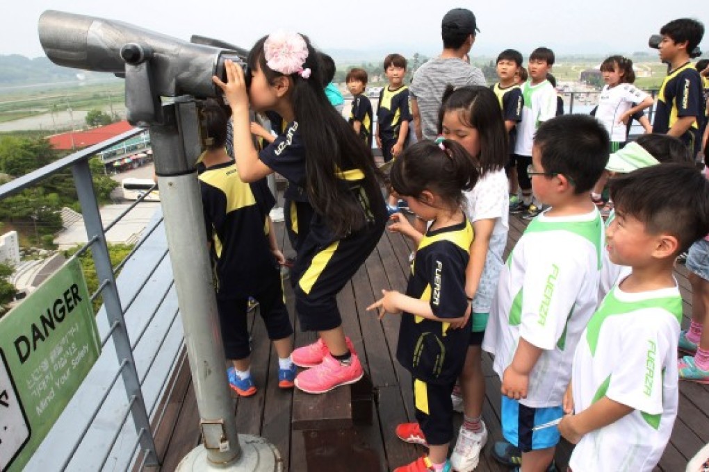 A young school pupil looks at North Korea through binoculars at the a pavilion near the border village of Panmunjom. Photo: AP