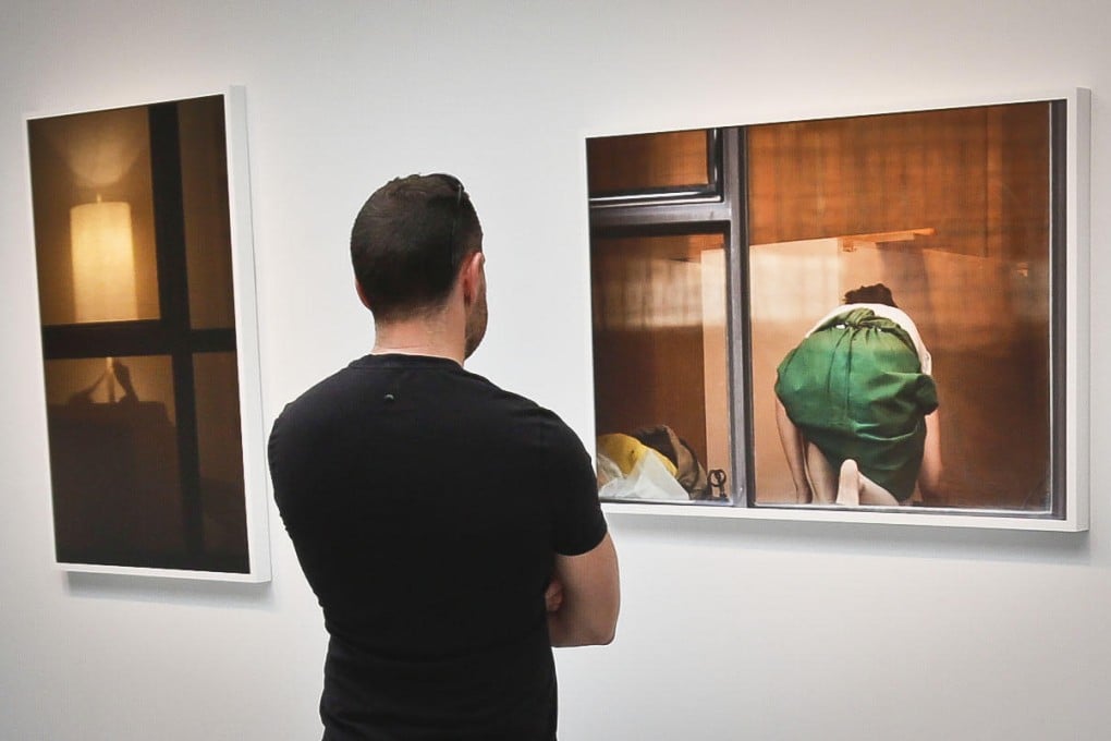 A visitor to Arne Svenson's exhibit in New York views a photograph taken without permission from the photographer's apartment. Photo: AP