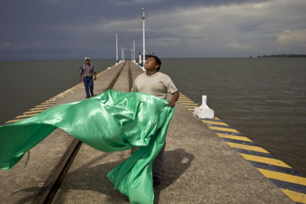 A worker prepares to hang a flag off Nicaragua Lake. A Chinese firm plans to build a canal that would go through the lake. Photo: AP