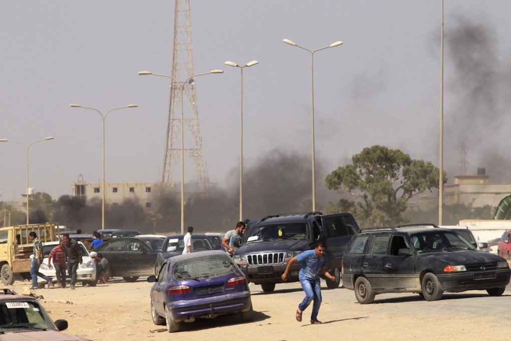 Protesters take cover during an attack on a Libyan militia headquarters in Benghazi. Photo: Reuters