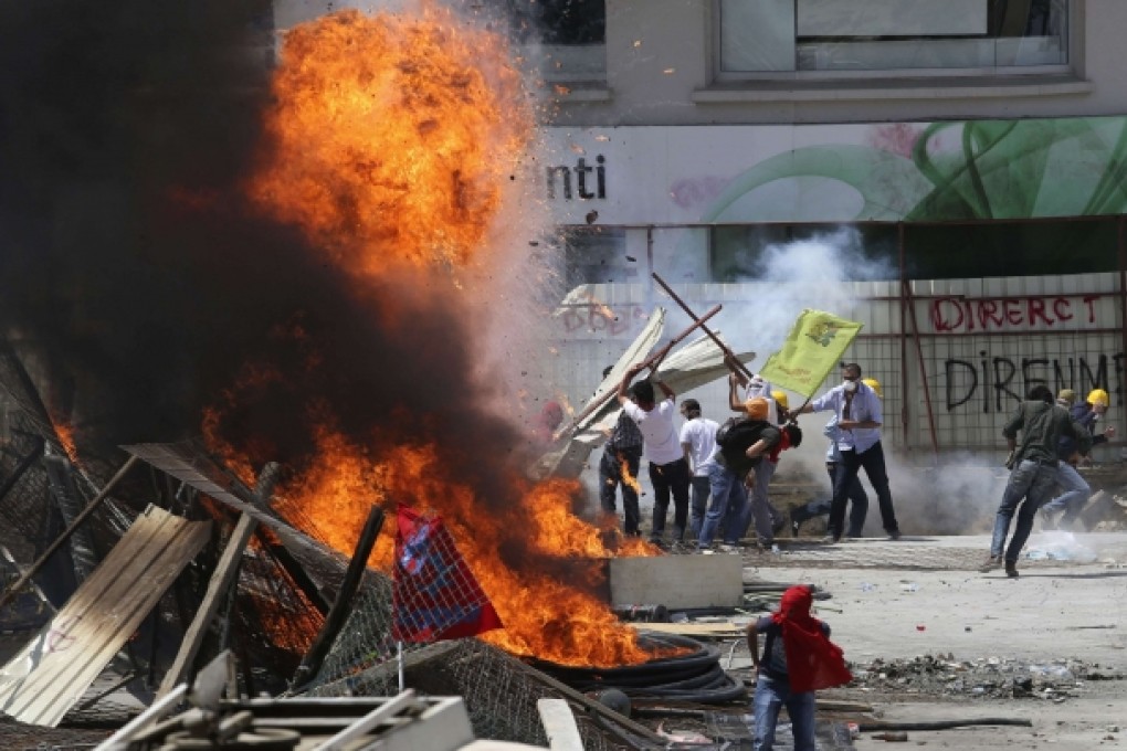 Protesters standing behind a barricade clash with riot police during a protest at Taksim Square. Photo: Reuters