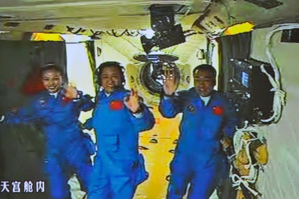 The screen at the Beijing Aerospace Control Centre shows the three astronauts waving hands at the Tiangong-1 space module as it docks with their Shenzhou-10 craft. Photo: Xinhua